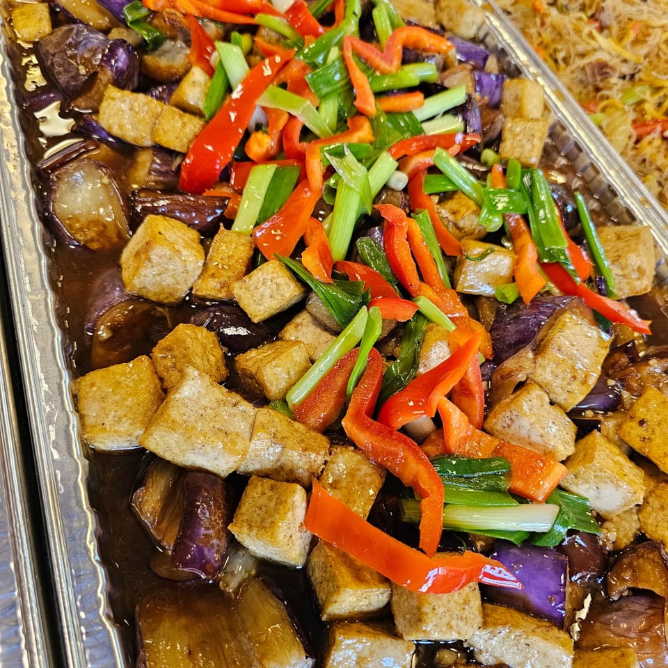 Filipino eggplant and tofu dish with red bell peppers and green onions in a dark sauce.