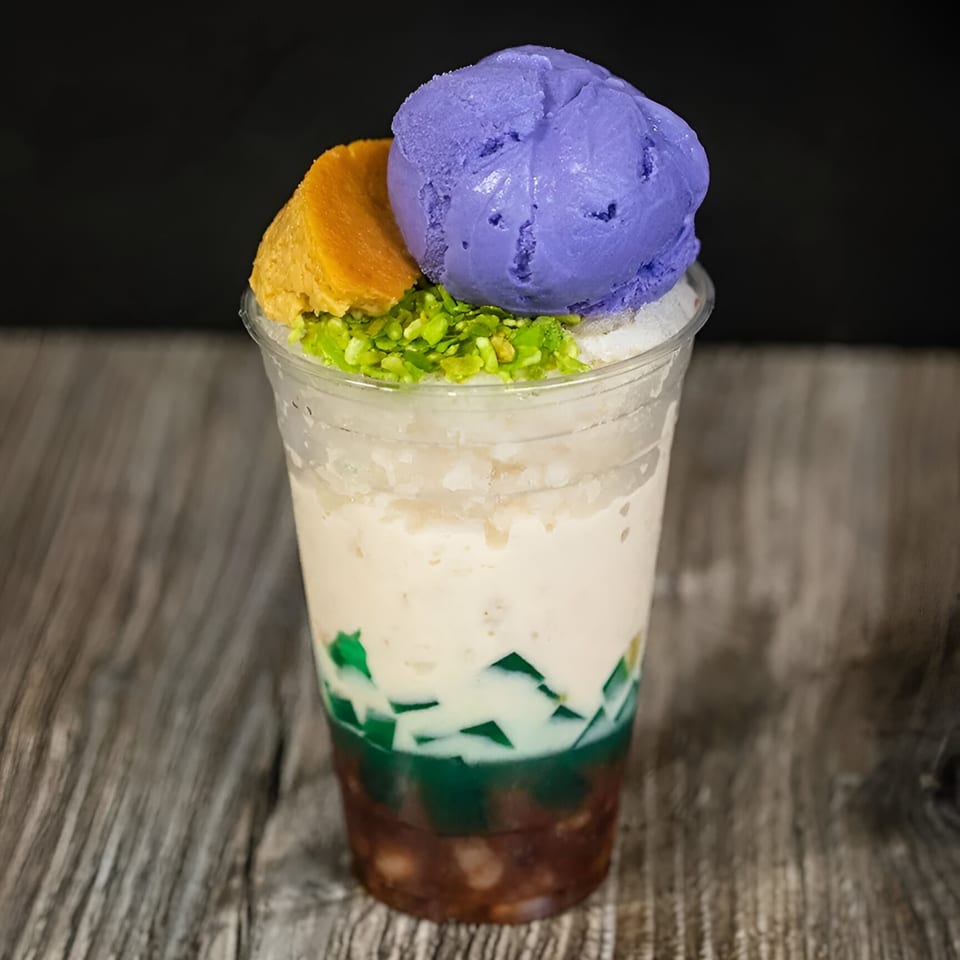 Halo-Halo dessert in a clear cup, topped with purple ube ice cream and leche flan.